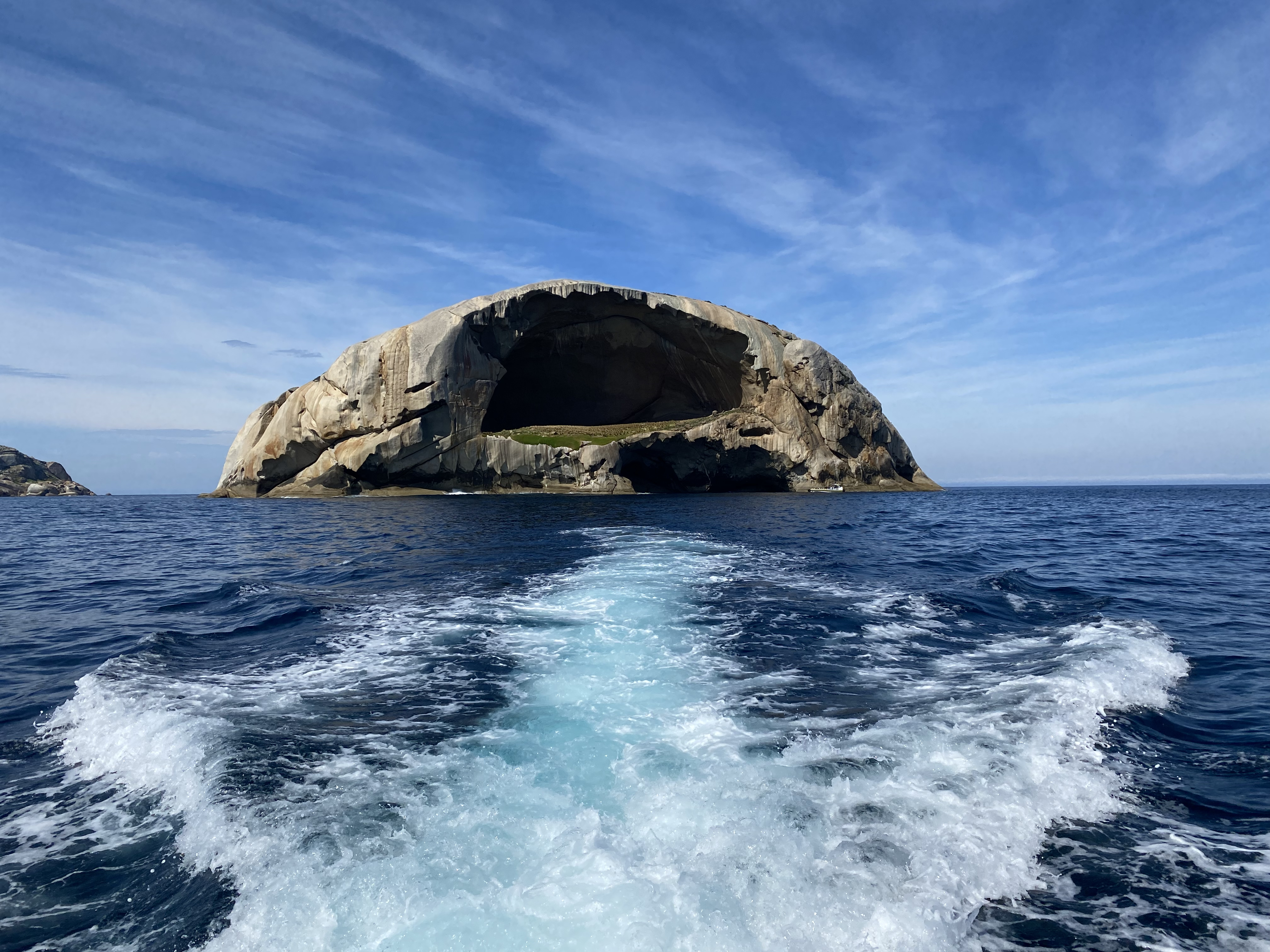 Skull Rock seen from the wake of a cruise boat